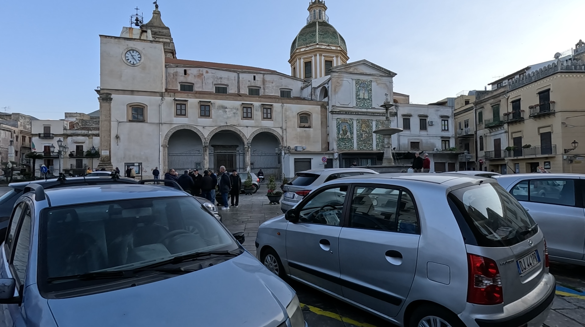 Town square in Carini Sicily with parked cars and locals enjoying daily life
