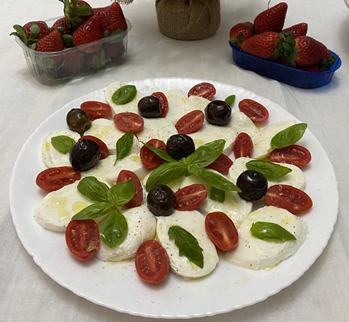 Caprese plate with homemade olives, cherry tomatoes, mozzarella, and basil prepared in Sicily