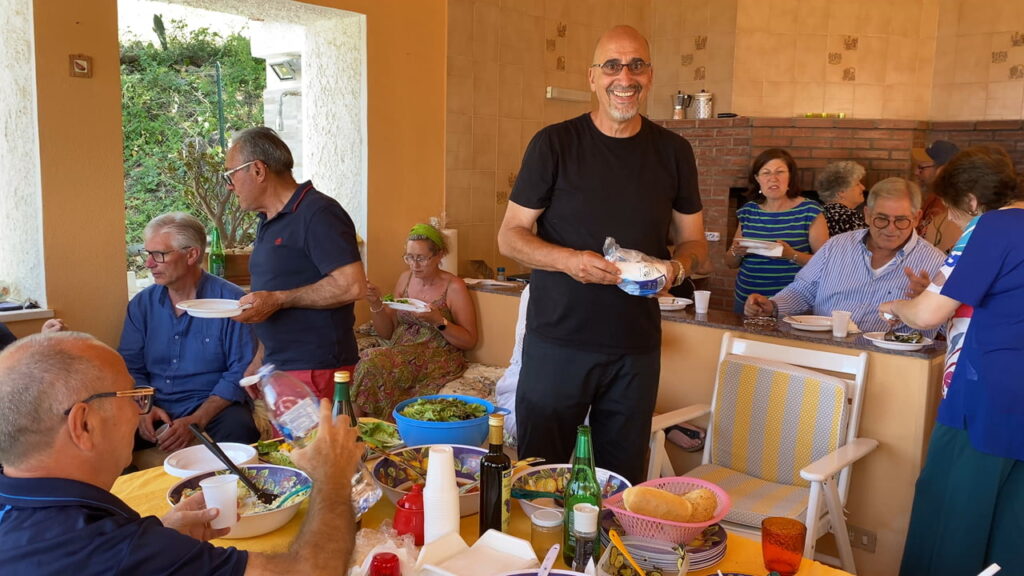 Friends sharing lunch in an outdoor kitchen and veranda in Sicily during daily life in Sicily