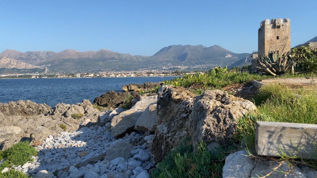 View of the Tyrrhenian Sea and the Carini coastline with the stone tower visible at Baglio di Carini while fishing in Sicily